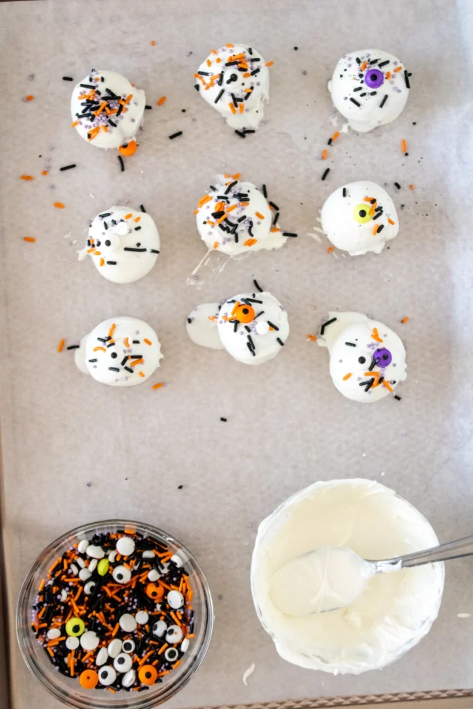 Halloween cake truffles fully coated and decorated with spooky sprinkles arranged on parchment paper