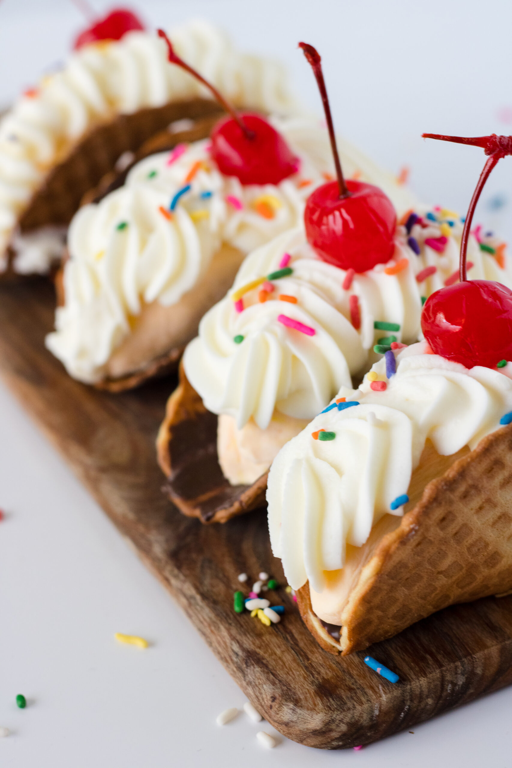 Banana split tacos made with waffle cone shells filled with creamy homemade banana ice cream topped with whipped cream and sprinkles.