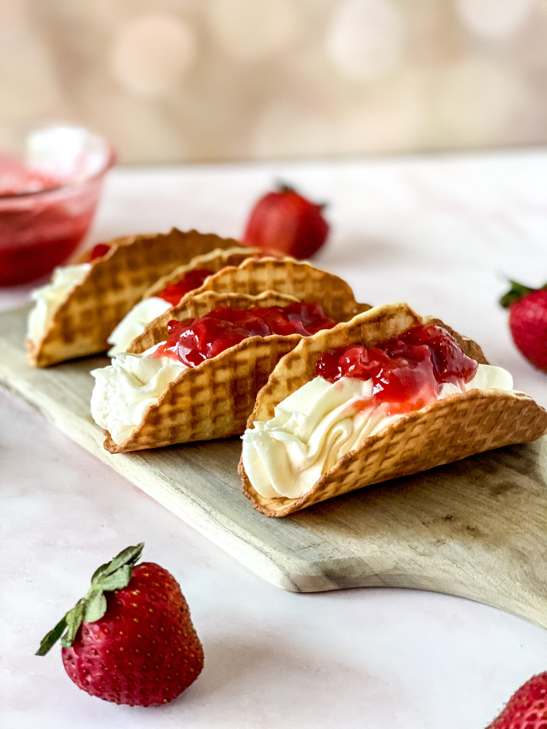 Strawberry cheesecake tacos filled with creamy cheesecake filling and topped with strawberry sauce.