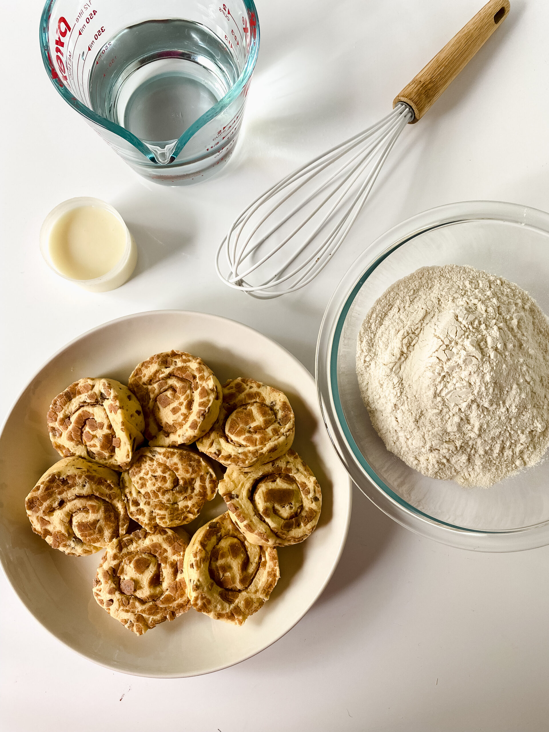 Ingredients for easy cinnamon roll pancakes including Grands cinnamon rolls, pancake mix, water, and icing.