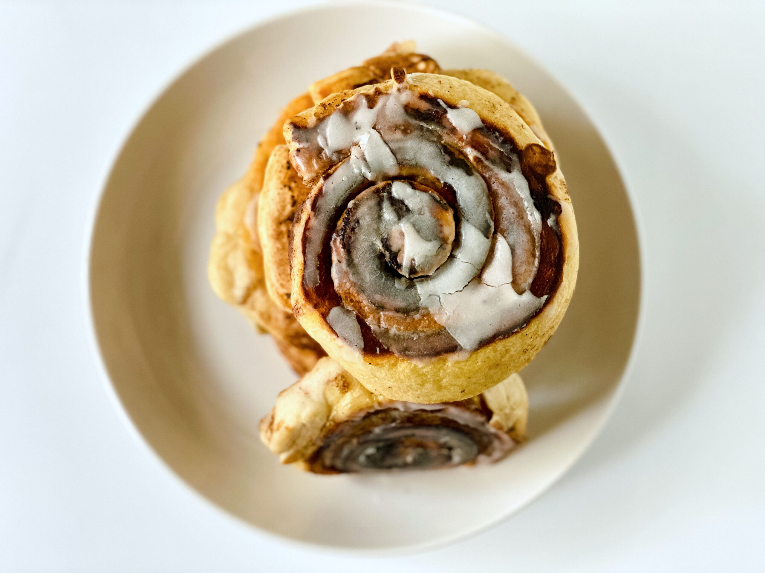 Stack of easy cinnamon roll pancakes topped with sweet icing on a plate.