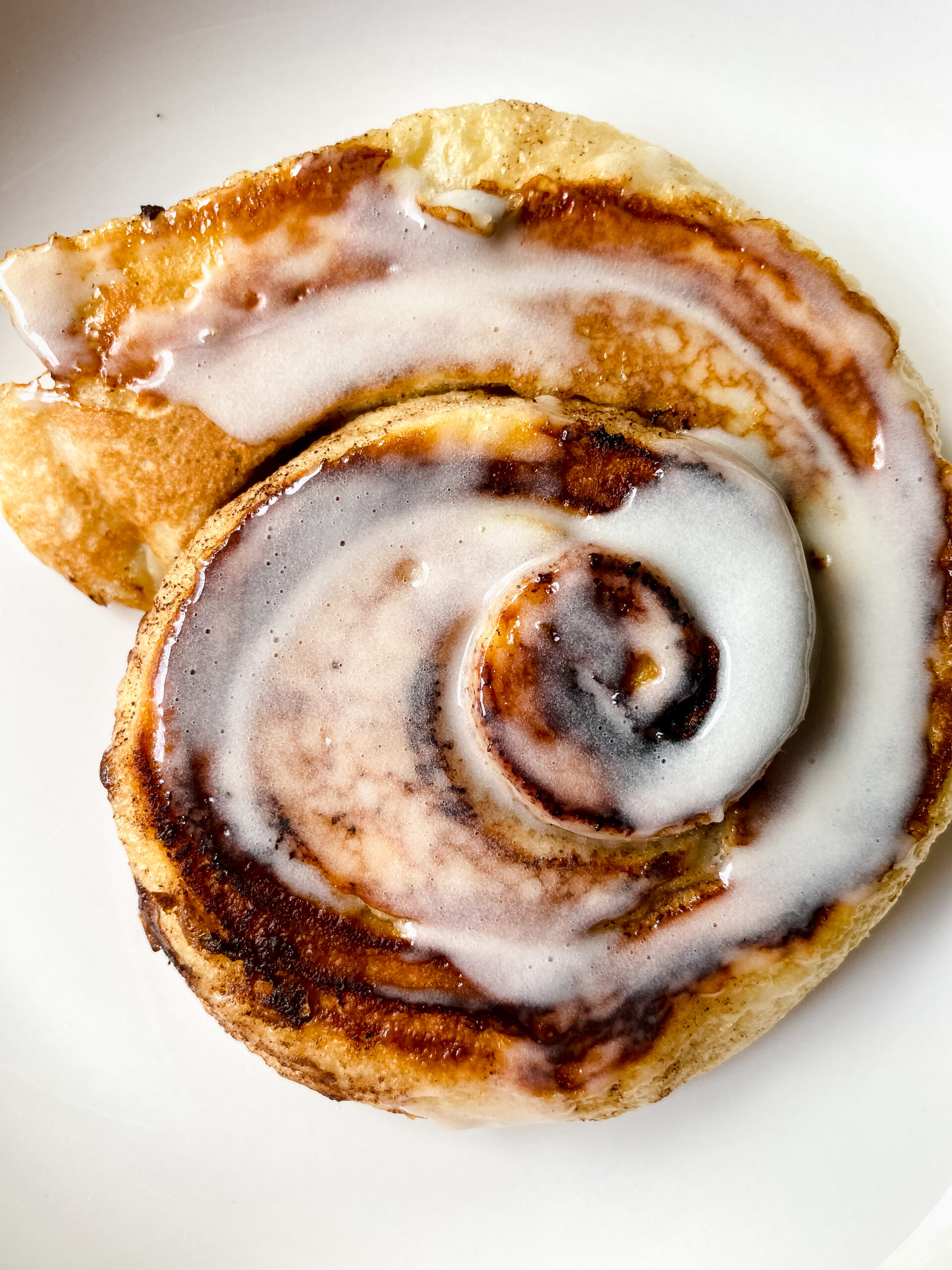 Warm cinnamon roll pancake topped with melted icing and ready to serve.