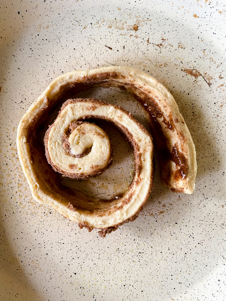 Unrolled Grands cinnamon roll in a skillet before adding pancake batter for easy cinnamon roll pancakes.