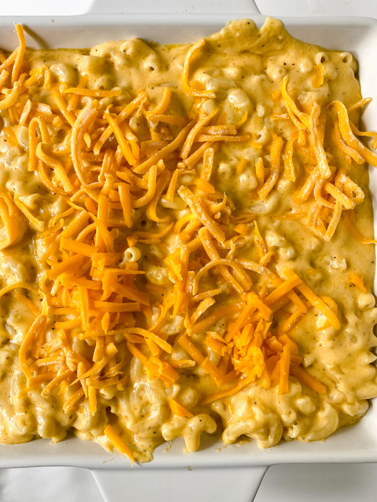 Shredded cheddar cheese sprinkled over macaroni and cheese before baking.