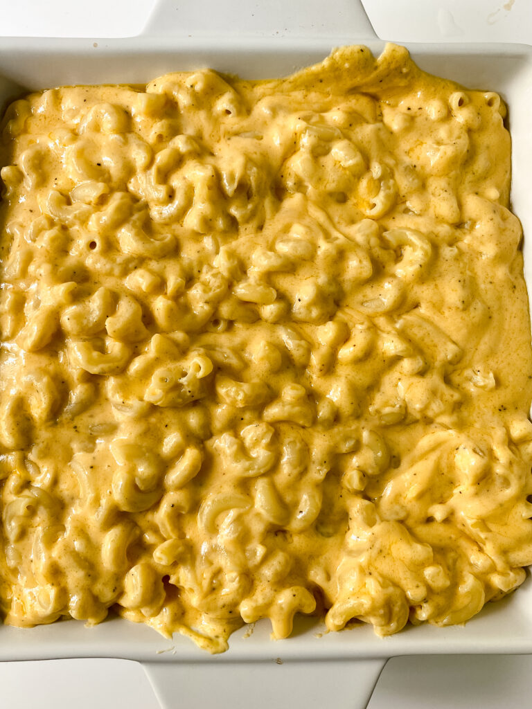 Creamy macaroni and cheese spread into a baking dish before baking.