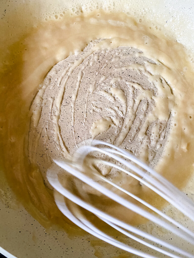 Whisking butter and flour together to create a roux for homemade baked macaroni and cheese.