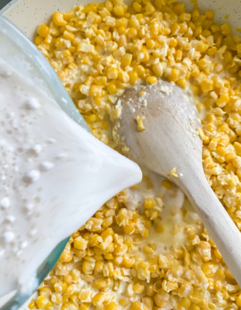 Milk and flour slurry being poured into creamed corn mixture to thicken the sauce.