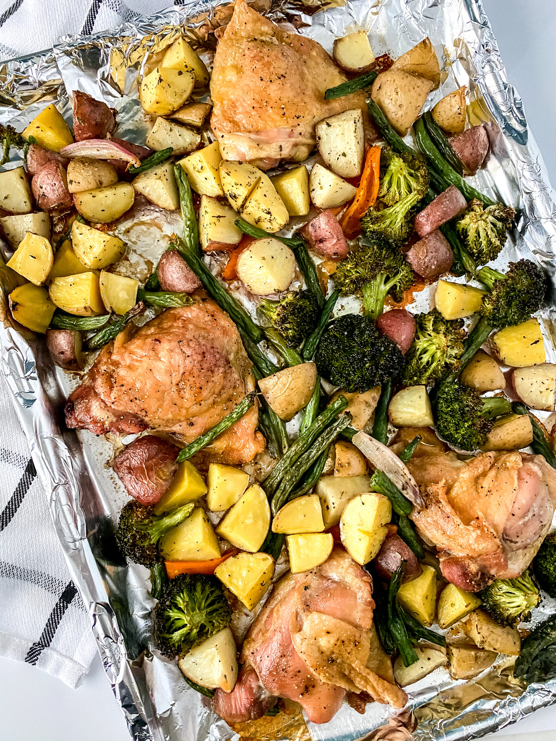 Oven-roasted chicken with colorful vegetables like carrots, potatoes, and broccoli on a sheet pan, cooked until golden and perfectly tender.