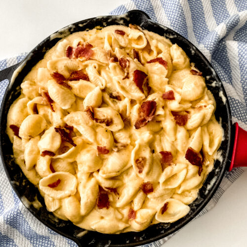 Creamy bacon mac and cheese topped and loaded with crispy bacon pieces, showing rich melted cheese and tender pasta in a comforting, golden-brown dish.
