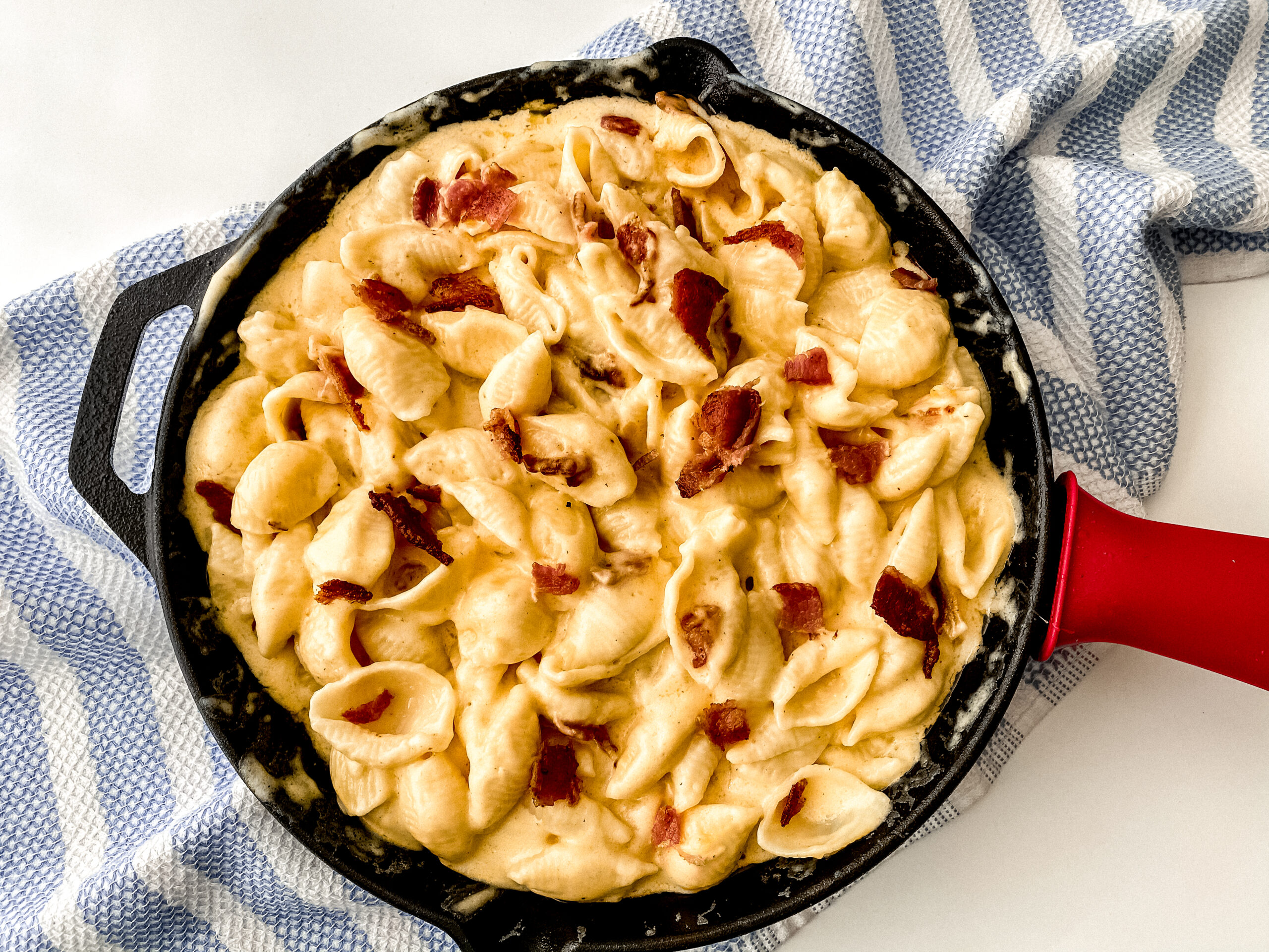 Creamy bacon mac and cheese topped and loaded with crispy bacon pieces, showing rich melted cheese and tender pasta in a comforting, golden-brown dish.