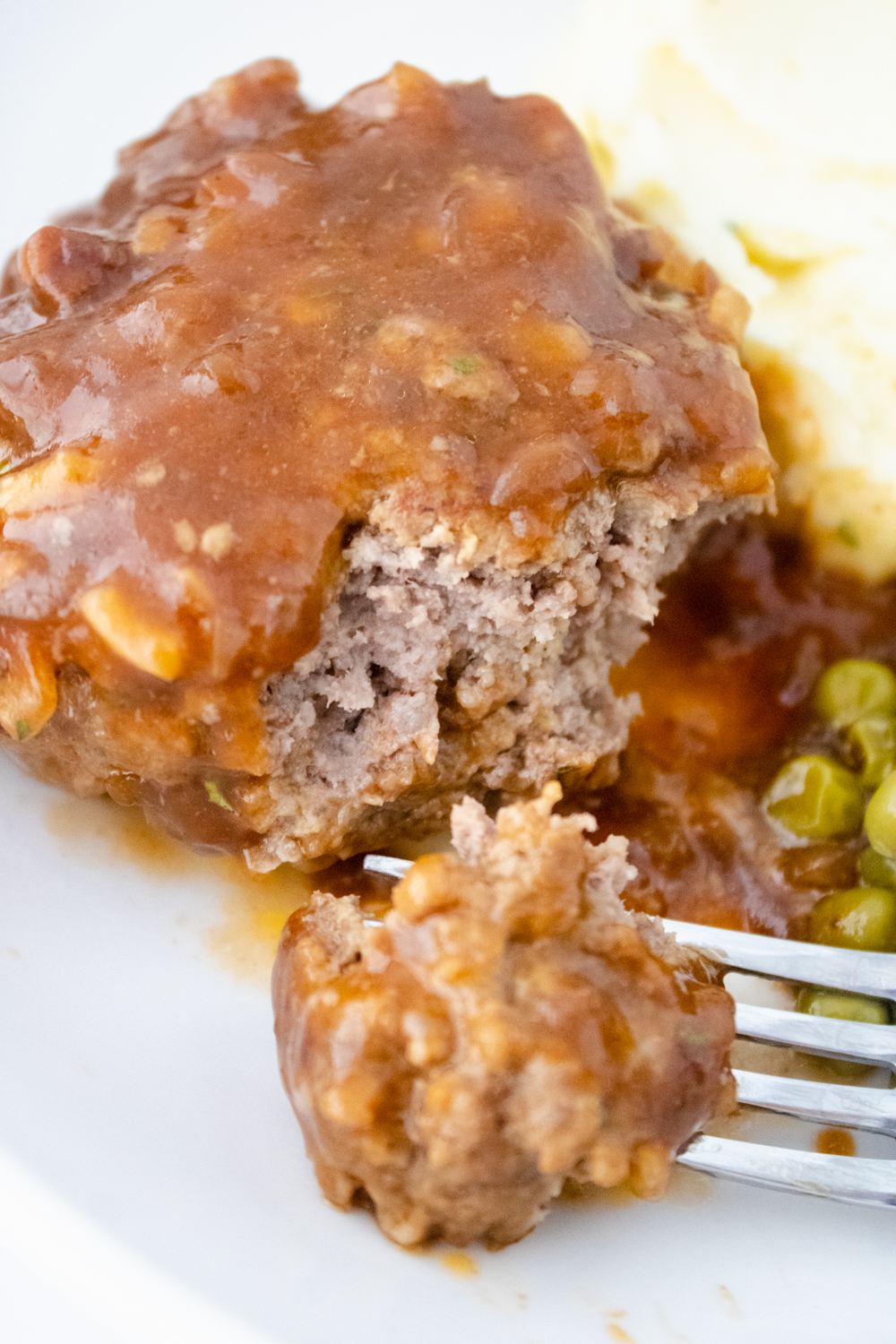 Homemade Salisbury steak covered in rich brown gravy with a bite missing to show the tender texture.