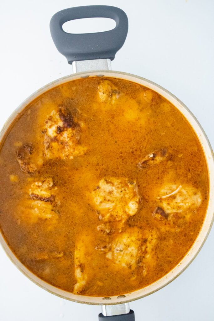 Seasoned chicken thighs returned to the skillet with broth and rice before simmering in one pot chicken and rice.