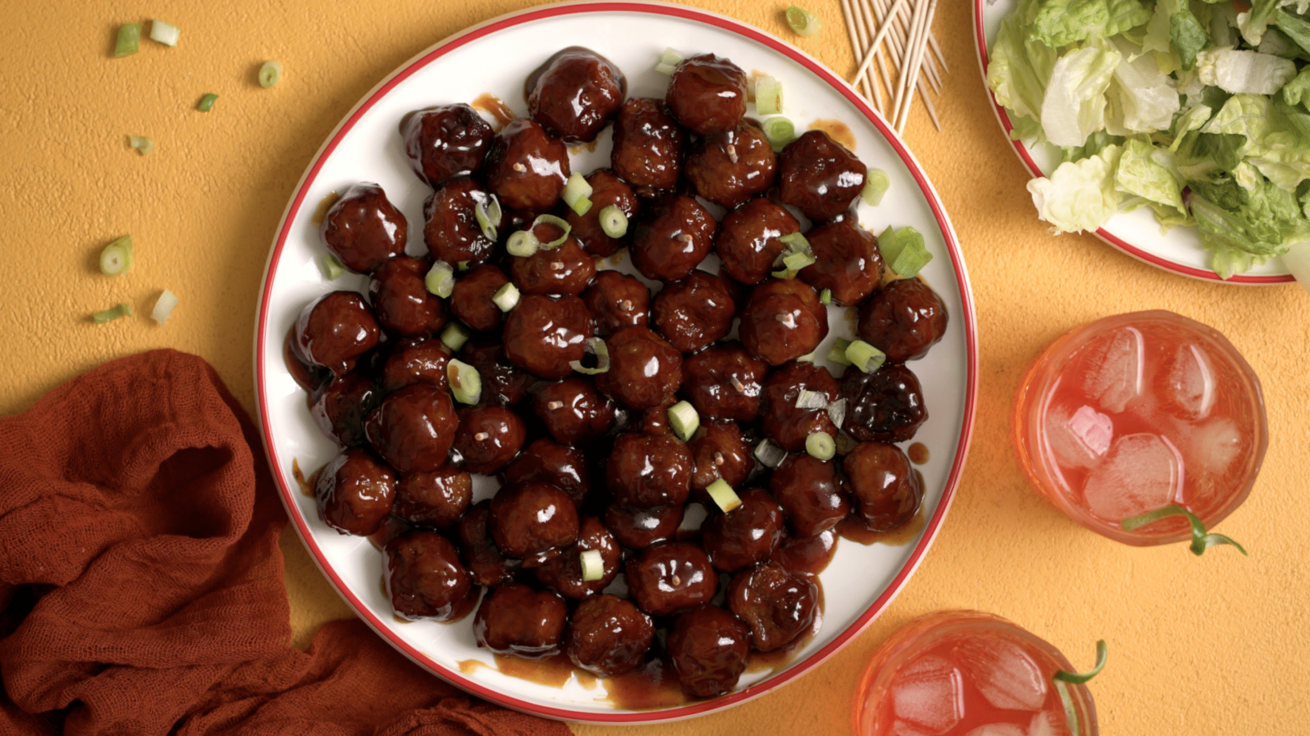 Oven-baked frozen meatballs coated in grape jelly and BBQ sauce, served on a platter with toothpicks for a party.