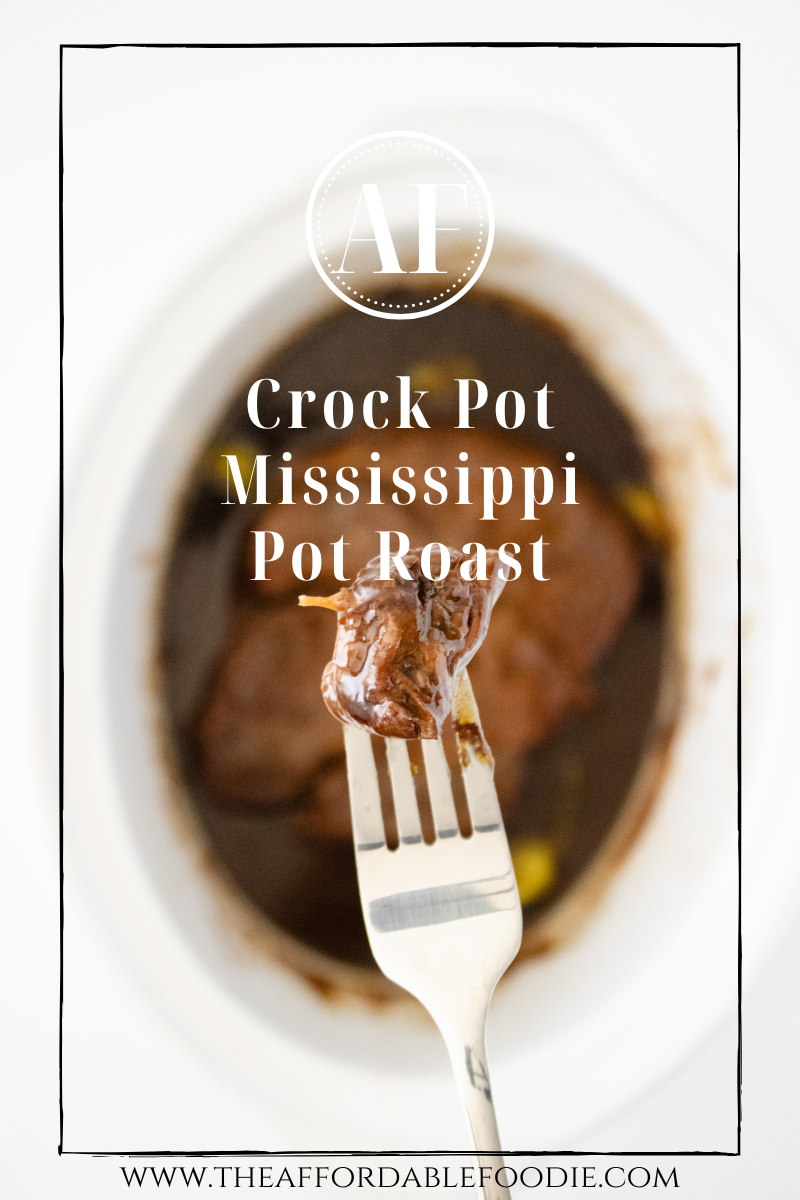 Close-up of a fork lifting a tender piece of Mississippi pot roast above a slow cooker filled with juicy shredded beef and pepperoncini peppers.