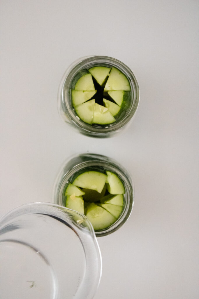 Adding brine to cucumbers to make pickles