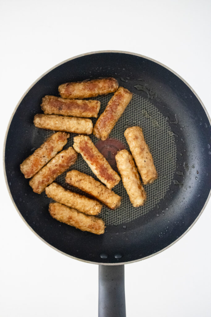 sausage links being cooked in frying pan