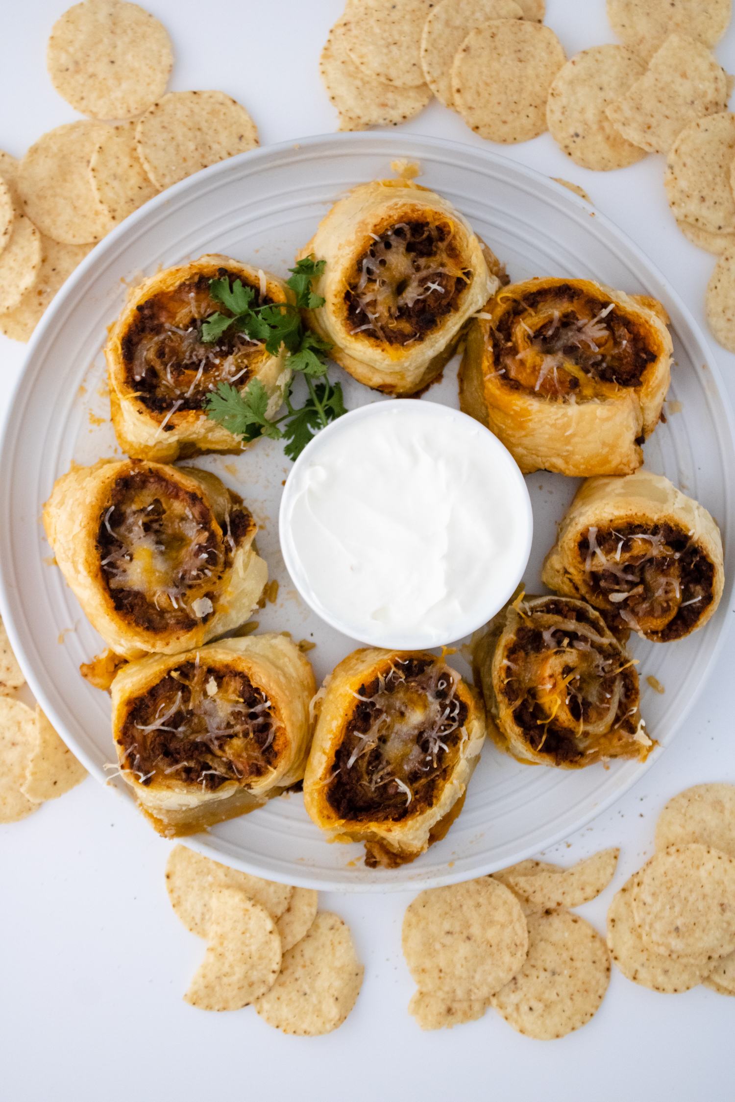 Taco pinwheels made with seasoned beef, cheese, and flaky pastry served with a creamy dipping sauce.