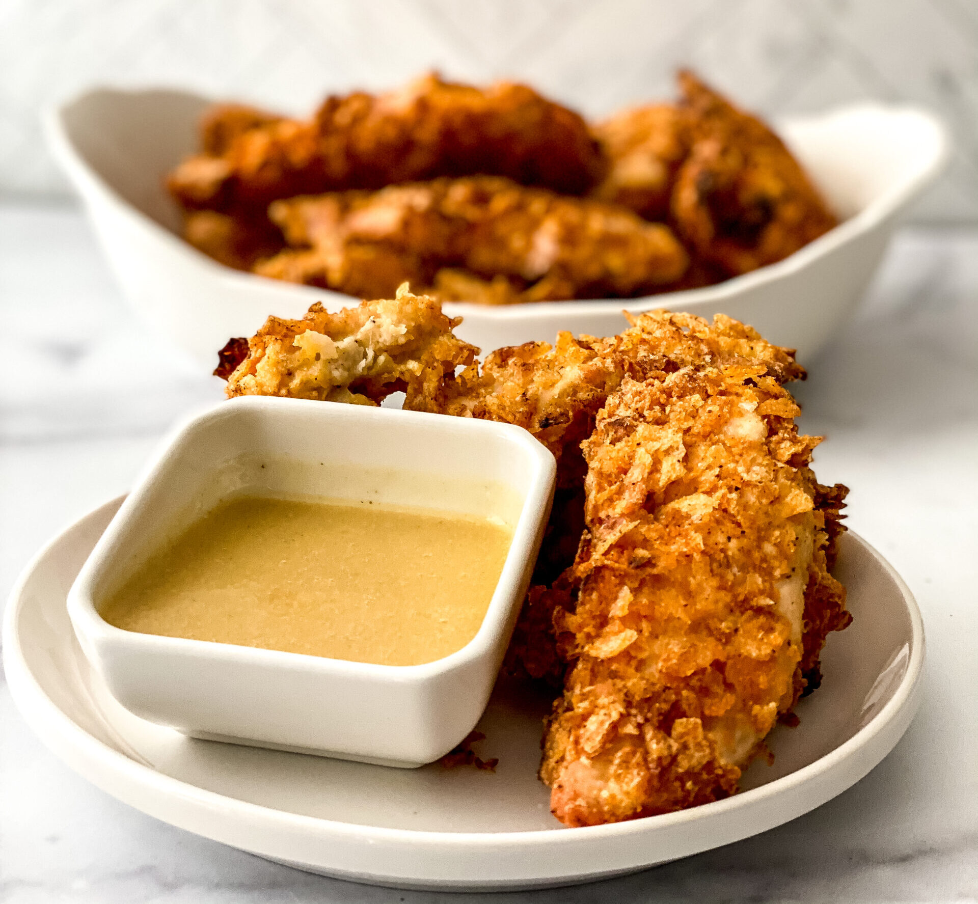 Crispy baked BBQ chicken tenders coated in crushed barbecue chips, baked to golden perfection, and served with dipping sauce for an easy family meal.