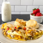 Veggie breakfast quesadilla filled with eggs, bell peppers, onions, and melted cheese served with biscuits and fresh strawberries.
