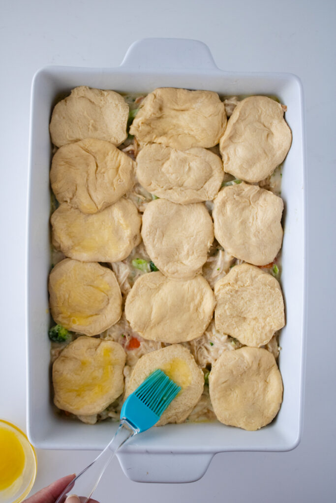 Biscuit dough arranged over chicken pot pie filling and brushed with melted butter before baking.