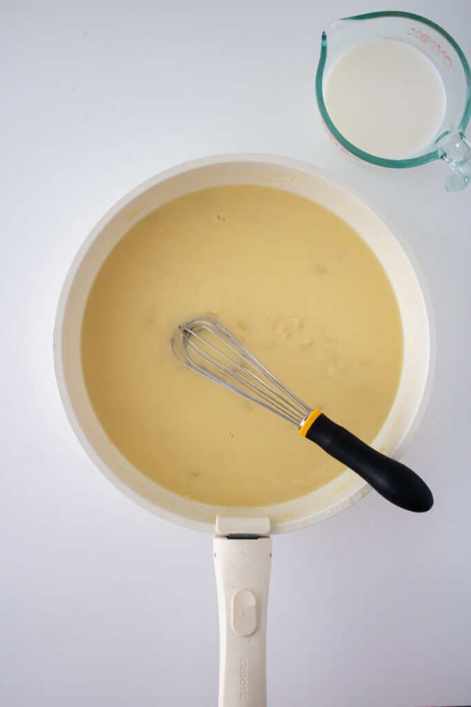 Milk being added to the chicken broth mixture in a skillet for chicken pot pie filling.