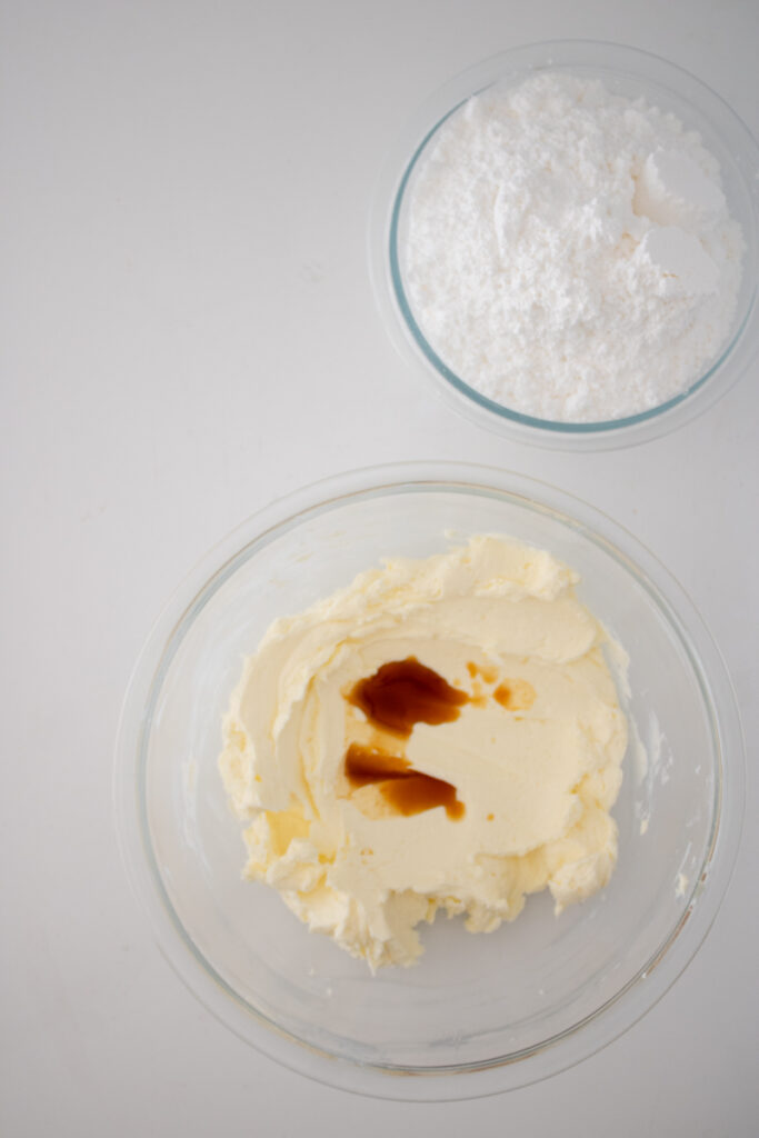 Vanilla extract being added to cream cheese frosting before mixing.