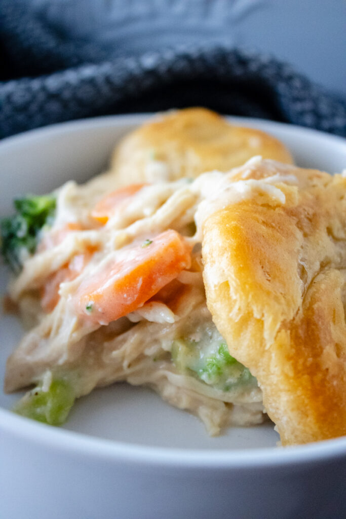 Close-up of chicken pot pie with biscuits showing creamy chicken filling, vegetables, and flaky golden biscuit topping.