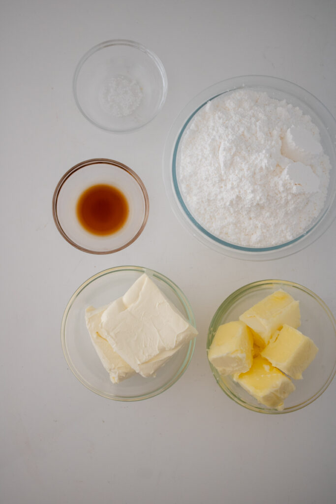 Ingredients for homemade cream cheese frosting including butter, cream cheese, powdered sugar, vanilla extract, and salt.