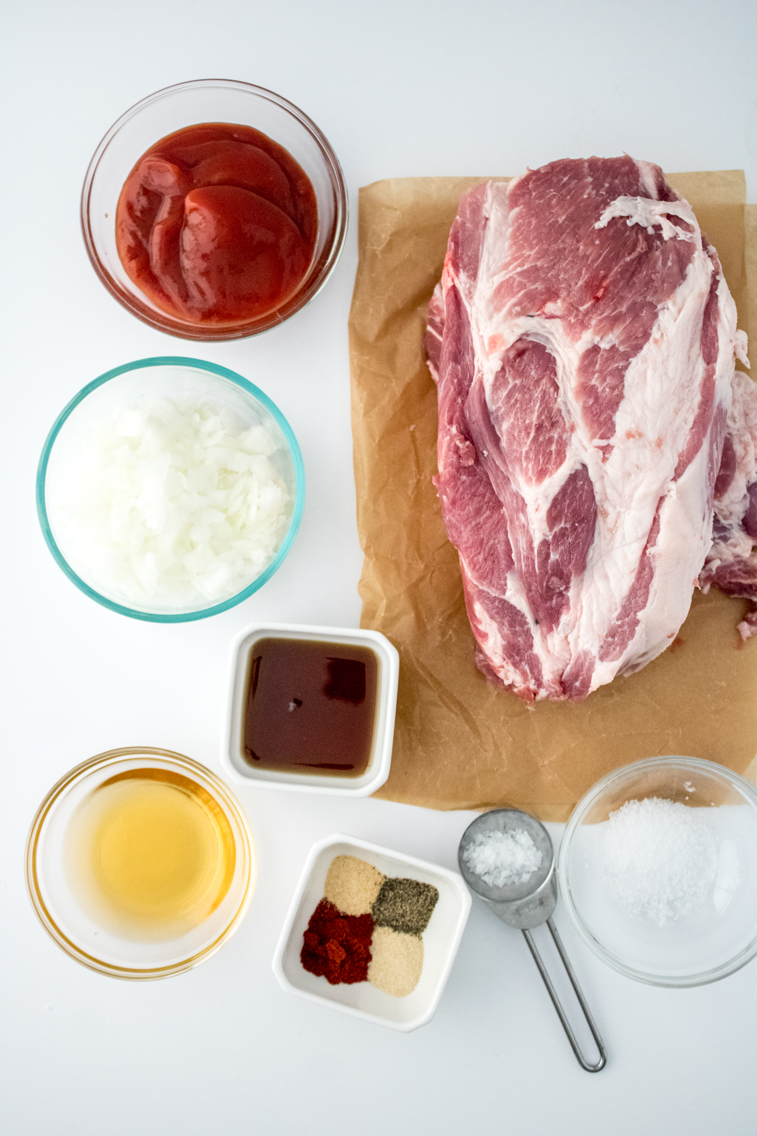 Ingredients for Crock Pot BBQ Pulled Pork including pork shoulder, ketchup, onion, apple cider vinegar, brown sugar, and seasonings.