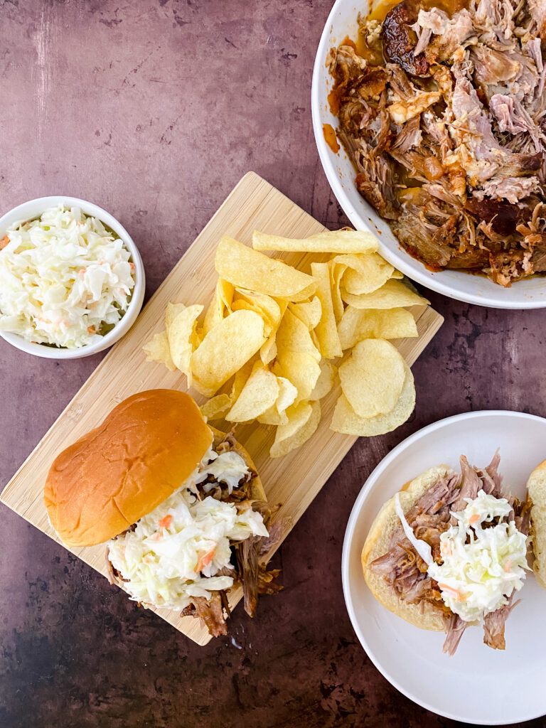 Crock Pot BBQ Pulled Pork served on sandwich buns with creamy coleslaw and potato chips.