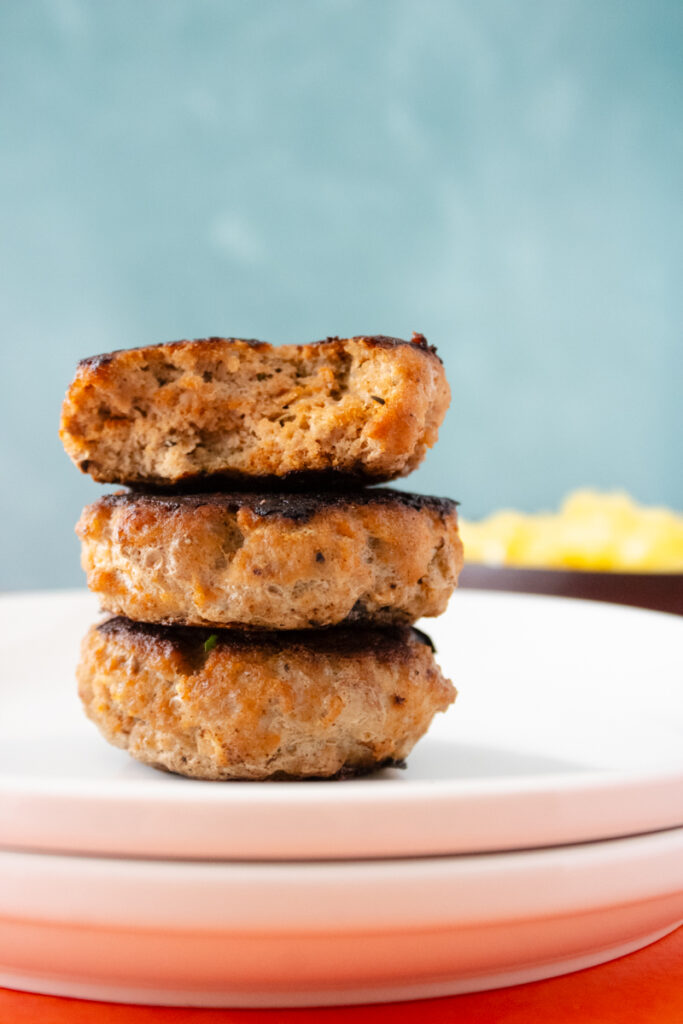 Stack of homemade turkey sausage patties with one cut open to show the juicy interior.