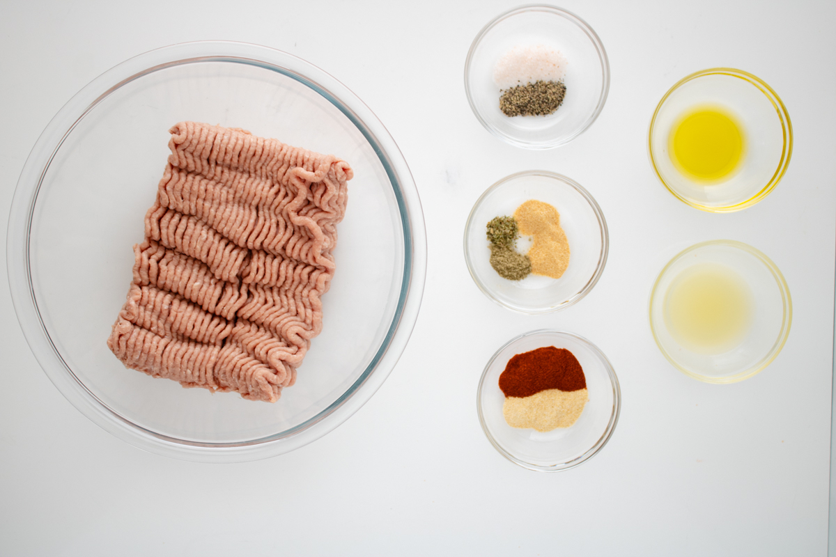 Ground turkey and simple pantry spices arranged in small bowls for making homemade turkey sausage.