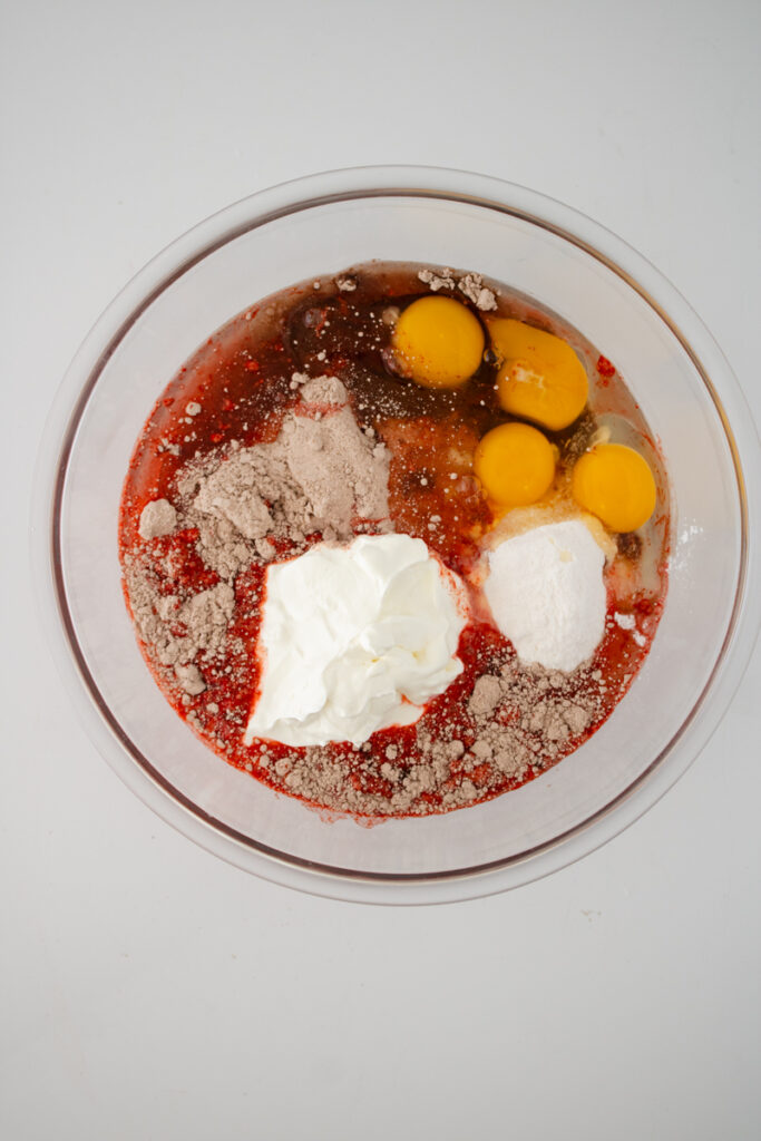 Red velvet cupcake ingredients combined in a mixing bowl before blending.