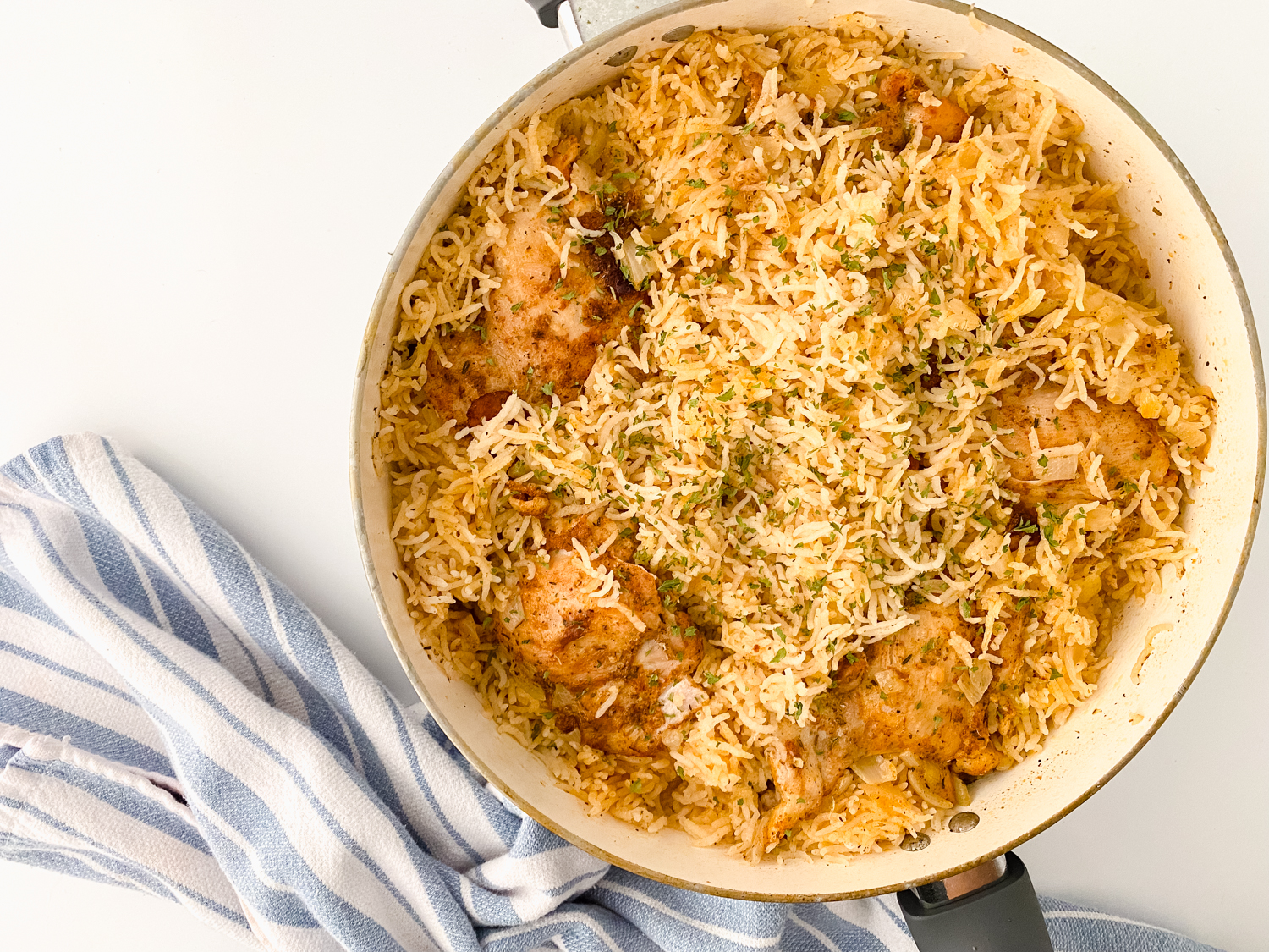 Overhead view of one pot chicken and rice made with seasoned chicken thighs, fluffy basmati rice, onions, and simple pantry spices cooked together in a large skillet.