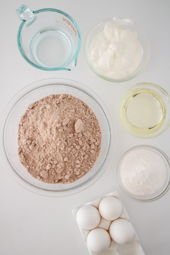 Ingredients for red velvet cupcakes from box mix including cake mix, white chocolate pudding, sour cream, eggs, oil, and water.