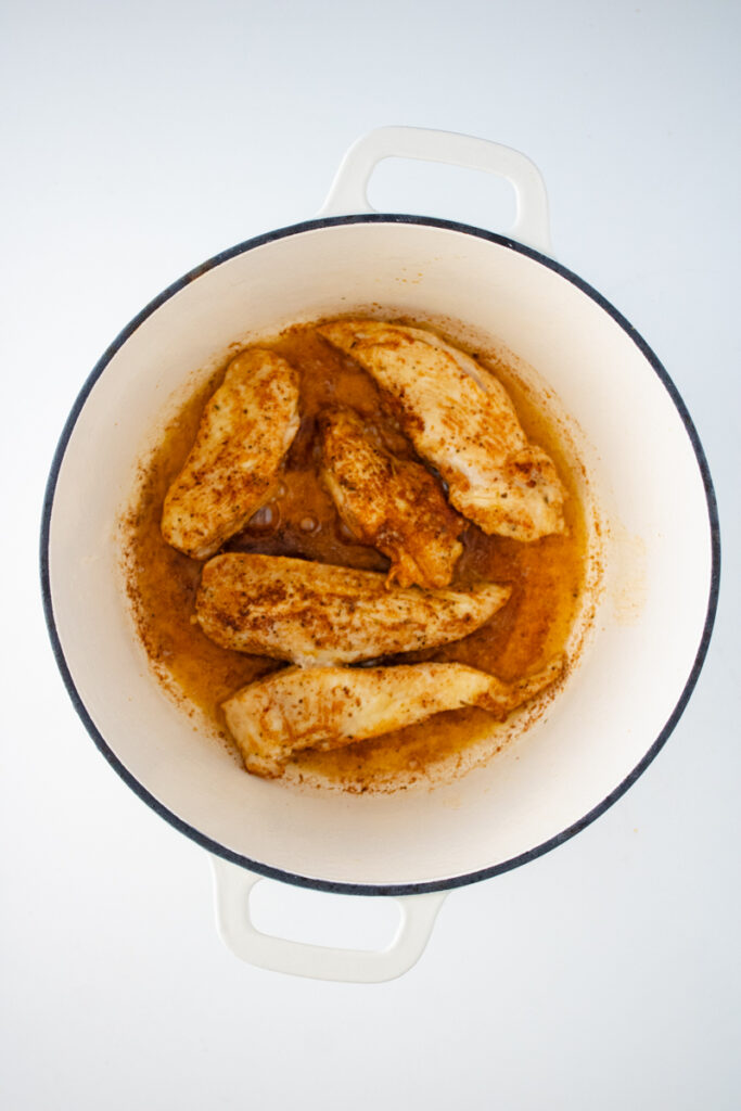 Seasoned chicken breasts searing in a Dutch oven for chicken and dumplings with biscuit mix.