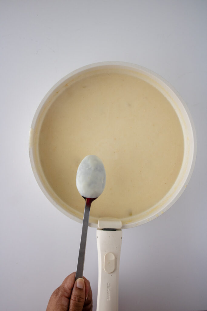 Thickened creamy chicken pot pie sauce coating a spoon in a skillet.
