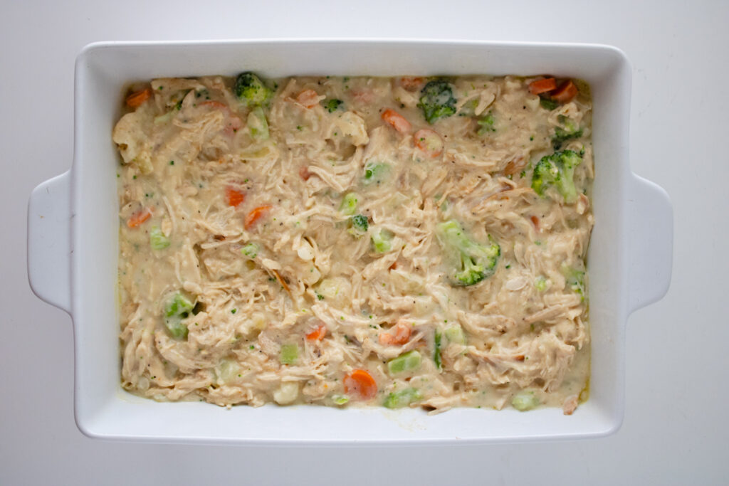 Chicken pot pie filling spread evenly in a 9x13 baking dish before adding the biscuit topping.