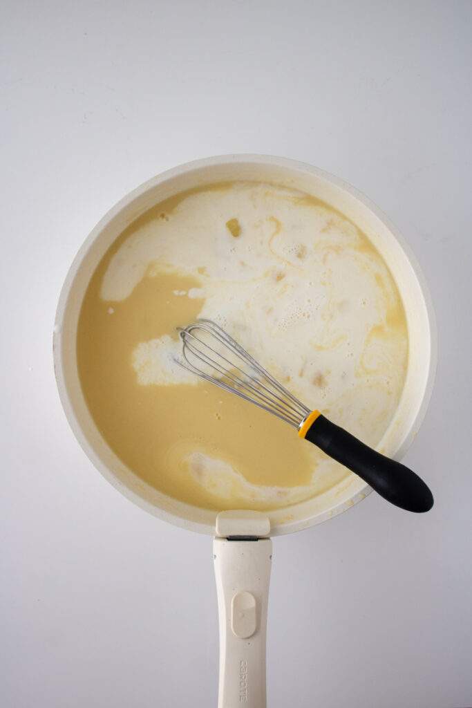 Chicken pot pie sauce being whisked in a skillet before thickening.